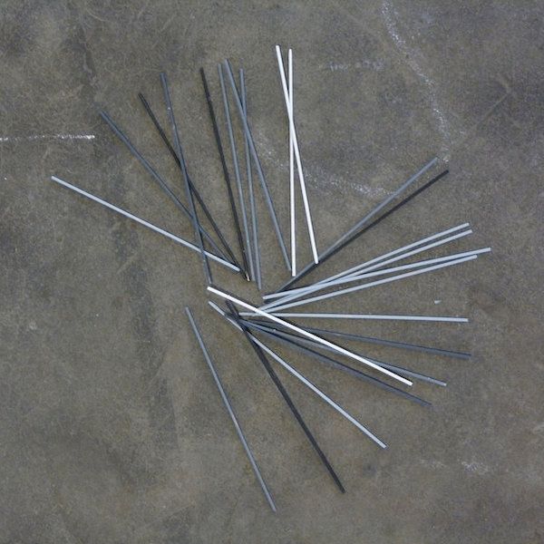 Des bâtonnets de mikado gris blancs et noirs sur un sol en béton